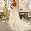 Abito da sposa da spiaggia personalizzato sexy con scollo a V profondo e cinturino per spaghetti con spalle scoperte senza maniche a trapezio in tulle con strascico