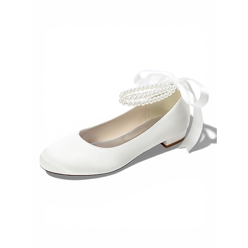 Elfenbeinfarbene, perlenbesetzte Ballerinas mit Knöchelriemen für Damen, elegante Brautschuhe im Ballerina-Stil für eine Hochzeit im Freien auf dem Rasen Image